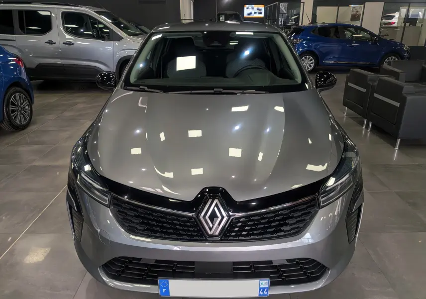 Vue avant d'une Renault Clio V TCe 90 Evolution gris schiste, avec calandre noire brillante et logo Renault central.