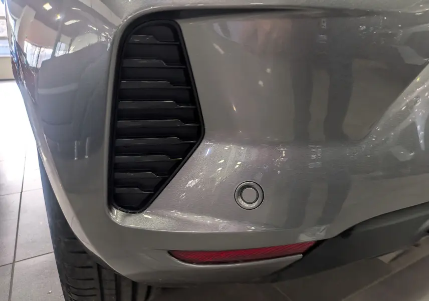 Gros plan sur le pare-chocs arrière droit gris schiste de la Renault Clio V TCe 90 CH Evolution avec capteur de recul.