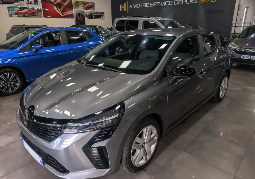 Renault Clio V TCe 90 Evolution gris schiste vue 3/4 avant droit en intérieur, avec phares LED distinctifs.