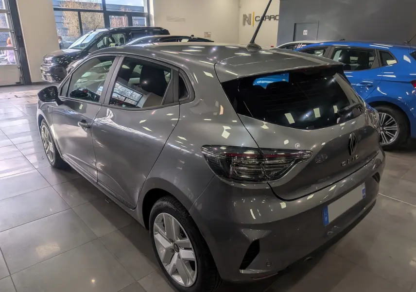 Renault Clio V TCe 90 Evolution gris schiste vue 3/4 arrière droit en intérieur, feux arrière LED et jantes alliage visibles.