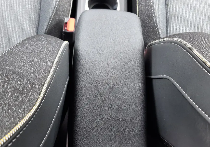 Vue rapprochée de l'accoudoir central noir entre les sièges tissu gris du Renault Captur E-Tech Full Hybrid 160ch Techno.