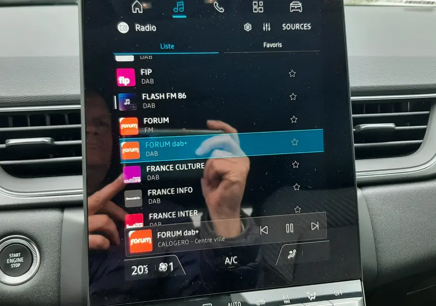 Écran tactile central du tableau de bord du Renault Captur E-Tech gris cassiopée, affichant la liste des radios DAB.