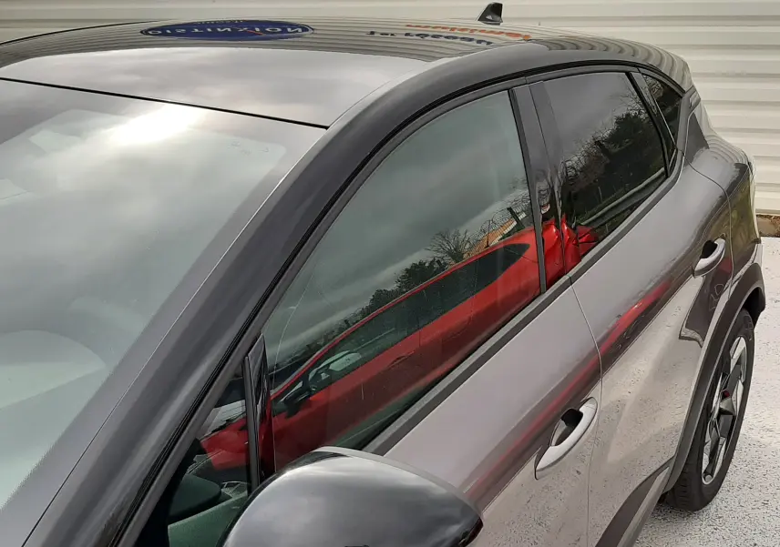 Vue de côté droit en gros plan du Renault Captur E-Tech Full Hybrid 160ch 2026 gris Cassiopée avec toit noir et rétroviseur noir brillant.