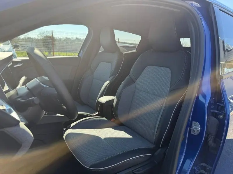 Vue intérieure côté conducteur de la Renault Clio 1.0 TCe 90ch Techno 2025 en Bleu Iron, sièges tissu avec surpiqûres blanches.