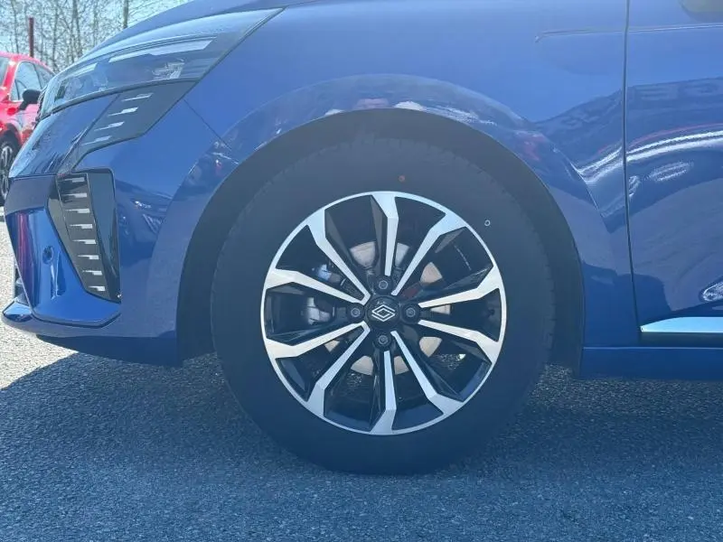 Gros plan sur la roue avant gauche d’une Renault Clio 2025 Bleu Iron, avec jante alliage au design moderne et partie du pare-chocs avant visible.
