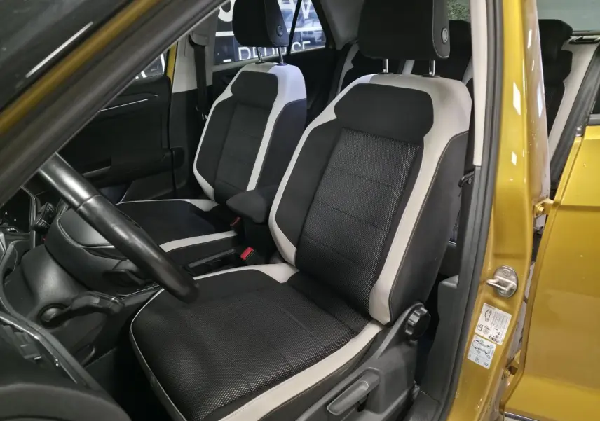 Vue intérieure côté conducteur du Volkswagen T-Roc jaune 2021, sièges tissu noir et beige avec volant cuir.