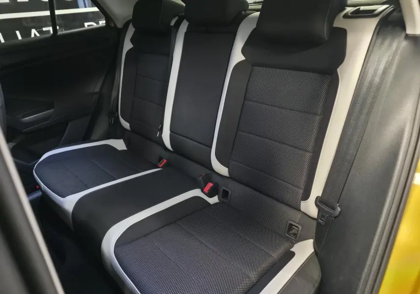 Vue intérieure de la banquette arrière noire et grise du Volkswagen T-Roc jaune 2021, avec ceintures de sécurité visibles.