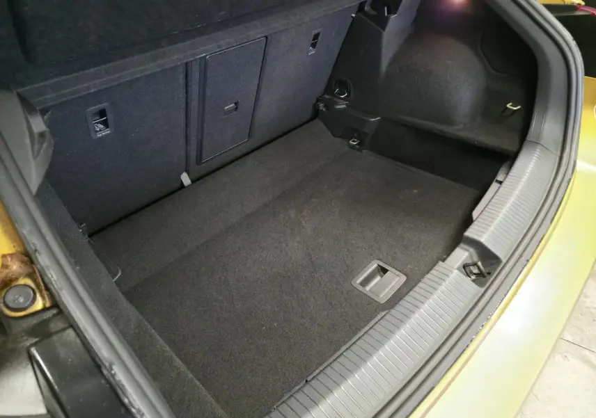 Coffre ouvert du Volkswagen T-Roc jaune, montrant l'espace de rangement intérieur et les finitions en tissu noir.