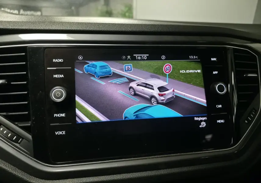 Écran tactile intérieur montrant l'assistance à la conduite avec véhicules en bleu et gris sur route virtuelle.