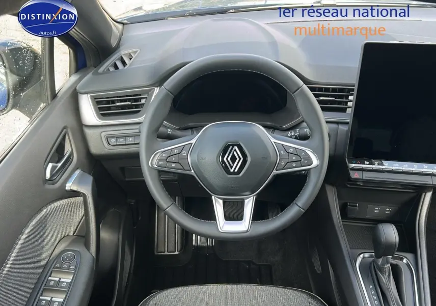 Vue intérieure centrée sur le volant multifonction et la console centrale du Renault Captur bleu iron 2025.