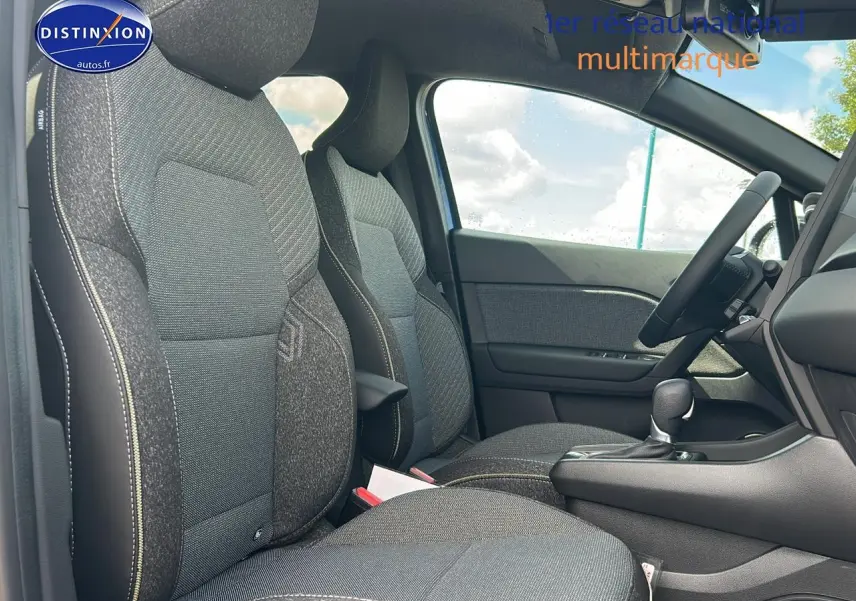 Vue intérieure côté conducteur du Renault Captur 2025, sièges tissu gris avec surpiqûres contrastées et console centrale noire.