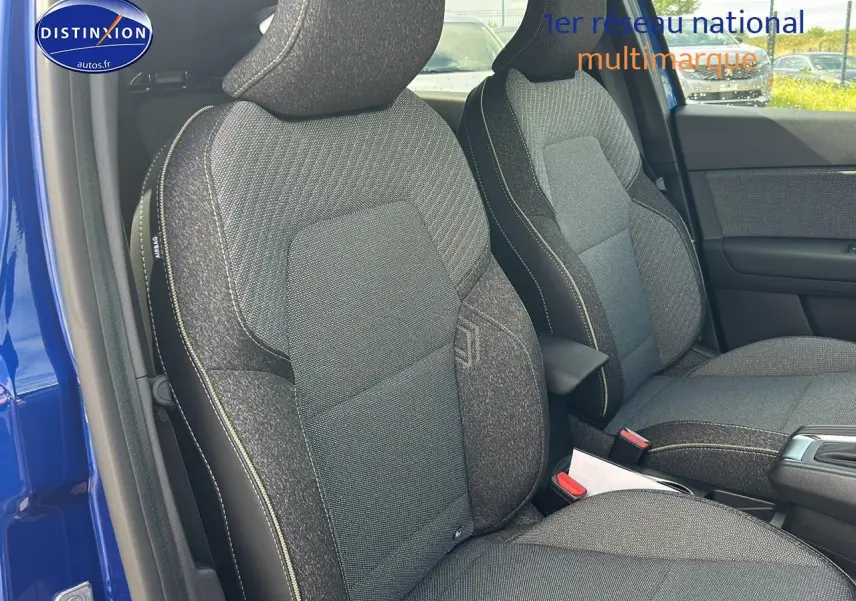 Vue intérieure côté conducteur du Renault Captur bleu iron 2025, mettant en valeur les sièges tissu gris et accoudoir central.