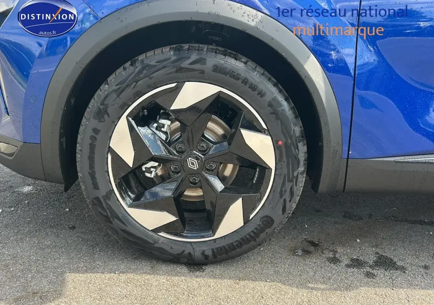 Gros plan sur la roue avant droite du Renault Captur bleu iron avec jante alu au design géométrique.