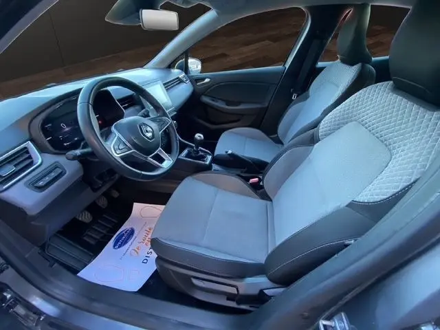 Vue intérieure côté conducteur de la Renault Clio gris foncé 2024, volant cuir multifonctions et sièges tissu gris clair.