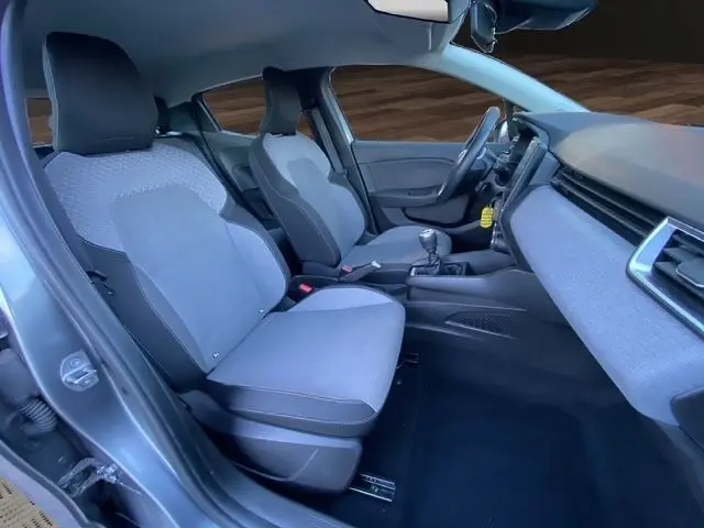 Vue intérieure côté conducteur de la Renault Clio Evolution TCe 90 2024 gris foncé, sièges tissu clair et tableau de bord moderne.