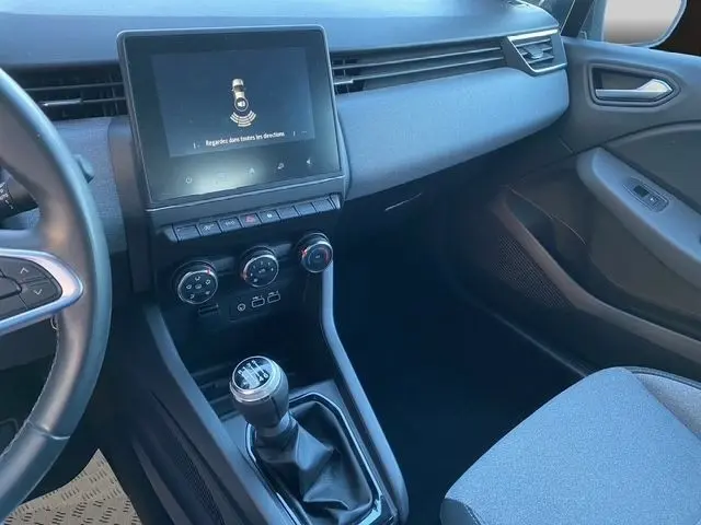 Intérieur avant droit de la Renault Clio Evolution TCe 90 gris foncé, avec écran tactile central et levier de vitesses manuel.