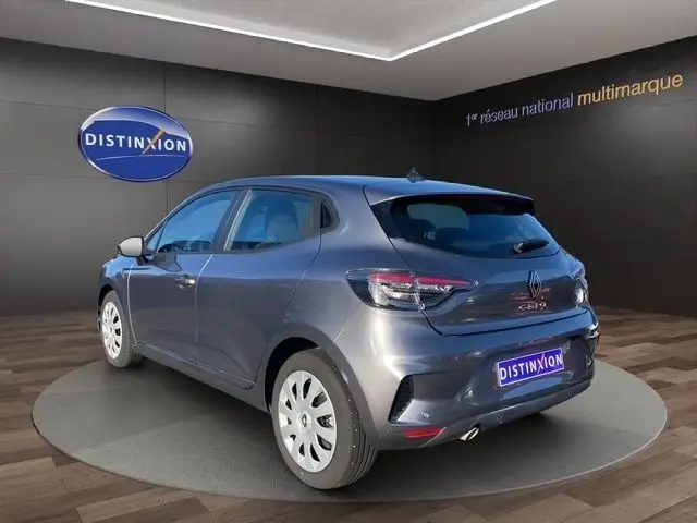 Vue 3/4 arrière droite d'une Renault Clio Evolution TCe 90 gris foncé, avec feux LED et jantes blanches en showroom.