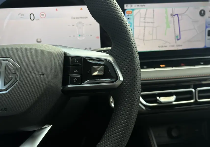 Gros plan sur le volant noir perforé MG EHS 1.5 Hybrid+ 224 Luxury avec tableau de bord numérique et écran tactile large.