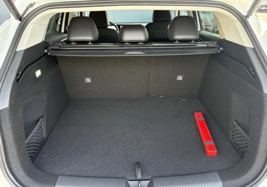 Coffre ouvert d’un MG Motor EHS blanc, vue arrière, avec tapis noir et triangle de signalisation rouge visible.