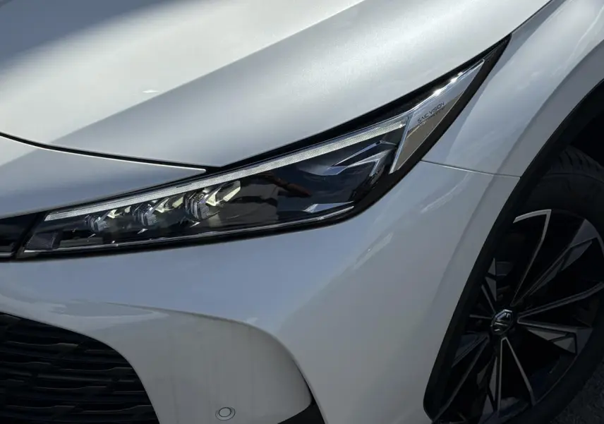 Gros plan sur le phare avant droit et la jante alliage noire du MG Motor EHS blanc métallisé 2026.
