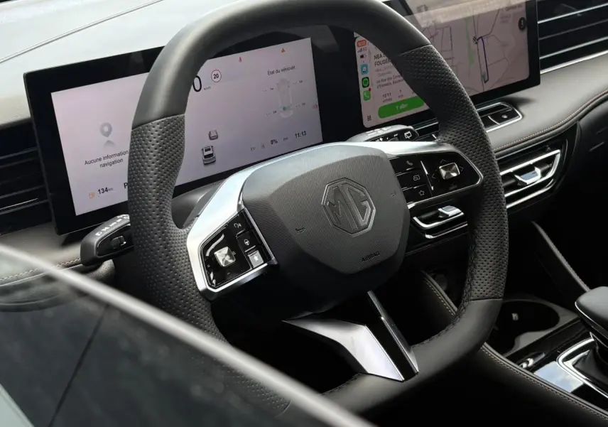 Vue rapprochée du volant noir perforé MG EHS 1.5 Hybrid+ 224 Luxury avec tableau de bord numérique et écran tactile.