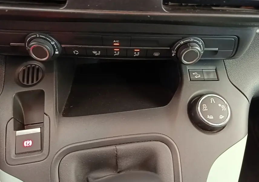 Gros plan sur la console centrale noire du Citroën Berlingo 2022, montrant les commandes de climatisation et frein à main électrique.