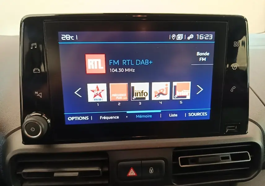 Écran tactile central affichant les stations radio dans l'habitacle du Citroën Berlingo blanc, vue de face.