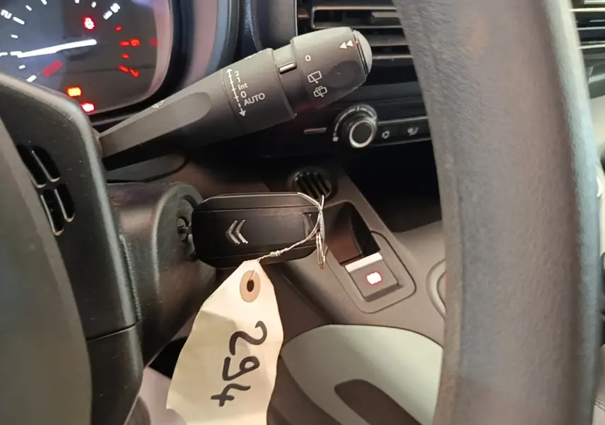 Gros plan intérieur sur le volant noir et la clé de contact du Citroën Berlingo blanc, avec tableau de bord partiellement visible.