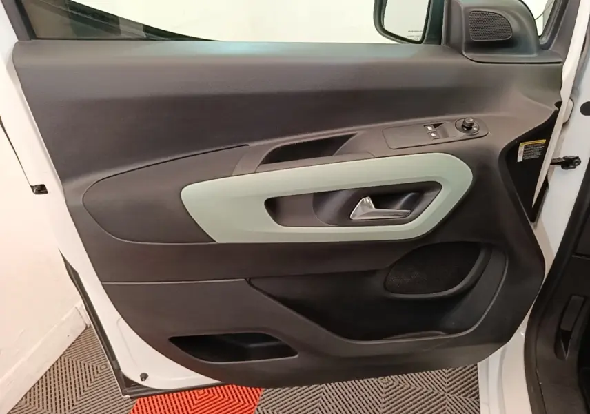 Vue rapprochée de la porte avant gauche blanche du Citroën Berlingo 2022 avec garniture intérieure noire et poignée grise.