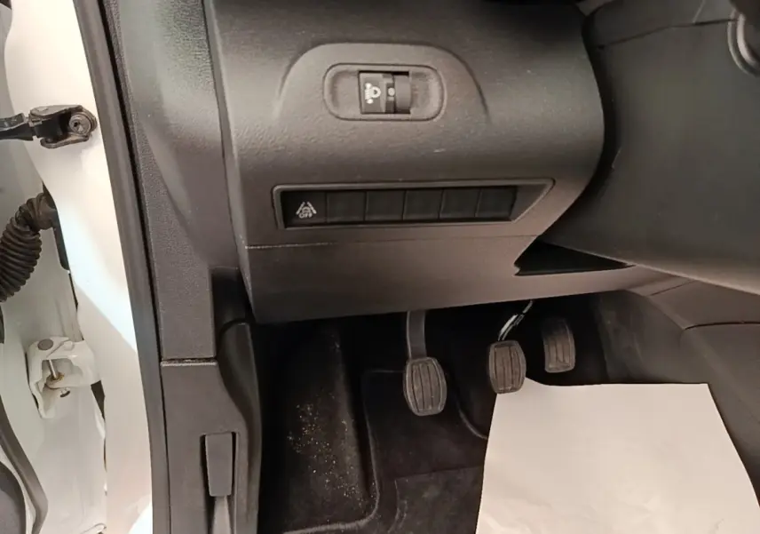 Vue intérieure côté conducteur du Citroën Berlingo blanc 2022, montrant les pédales et commandes sous le tableau de bord.