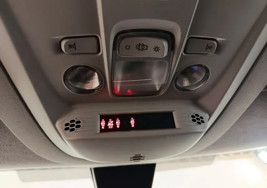 Vue intérieure en plongée du plafonnier gris clair du Citroën Berlingo blanc avec éclairages et indicateurs rouges allumés.