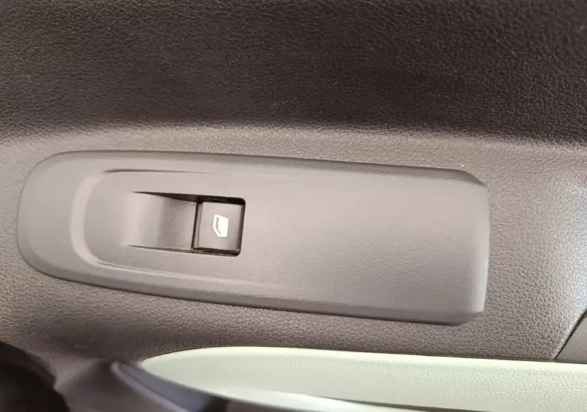 Gros plan sur l'interrupteur de lève-vitre côté conducteur dans l'habitacle noir et gris du Citroën Berlingo blanc.