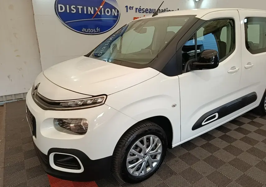 Vue 3/4 avant droite d'un Citroën Berlingo blanc avec protections latérales noires et jantes alliage.