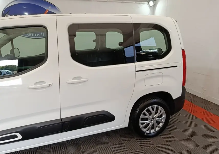 Vue latérale droite d'un Citroën Berlingo blanc 2022 avec protections noires sur les portières et jantes alliage.