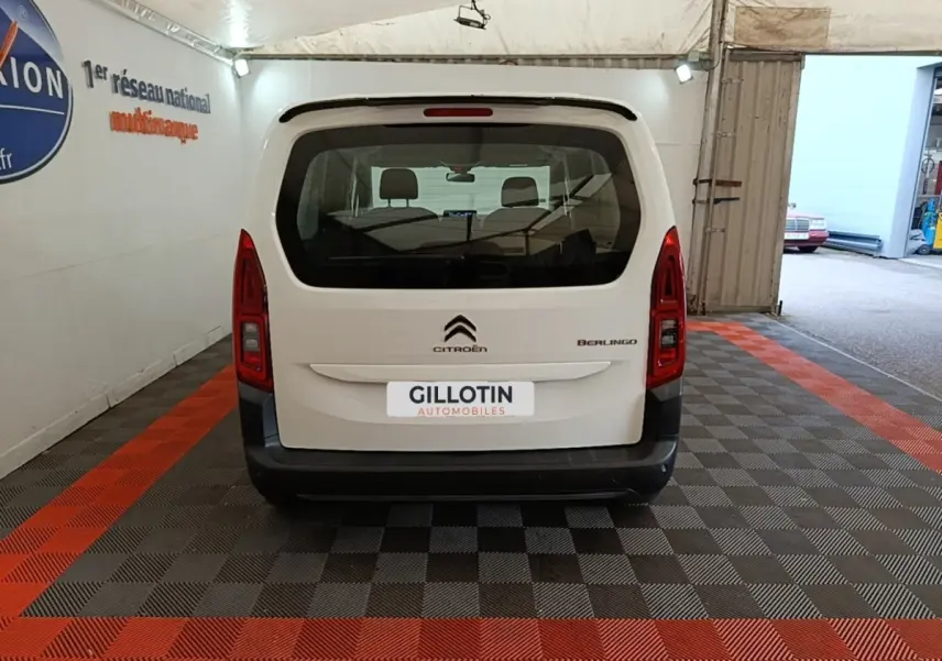 Vue arrière d'un Citroën Berlingo blanc garé en intérieur avec logo et feux verticaux rouges visibles.