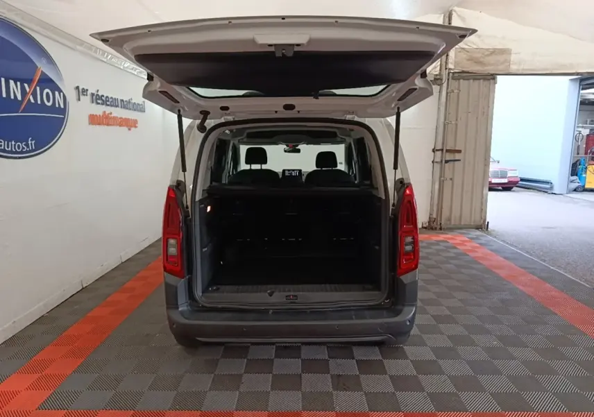 Vue arrière d'un Citroën Berlingo blanc 2022 avec hayon ouvert montrant le coffre vide dans un garage.