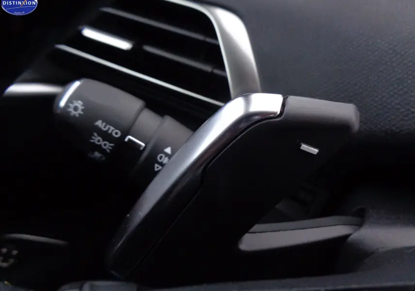 Gros plan sur la palette de changement de vitesse noire et argentée du Peugeot 3008 gris platinium 2023, côté gauche du volant.