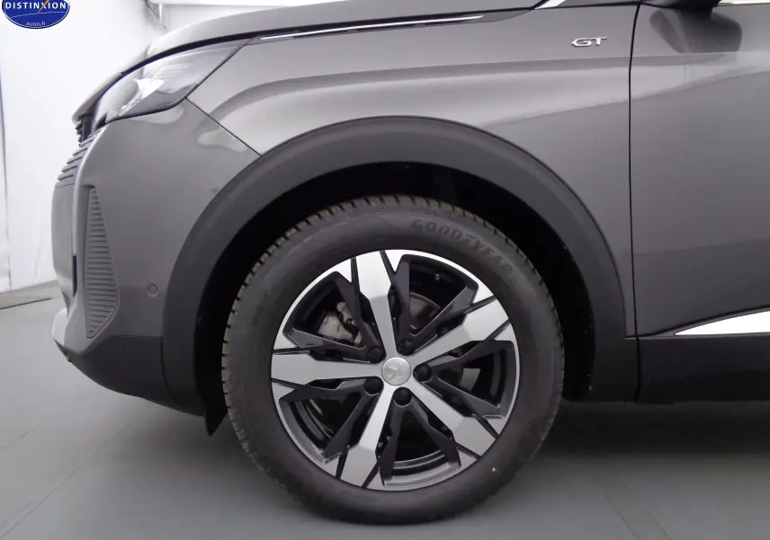 Gros plan sur la roue avant gauche et l'aile gris platinium d'un Peugeot 3008 GT avec logo GT visible.