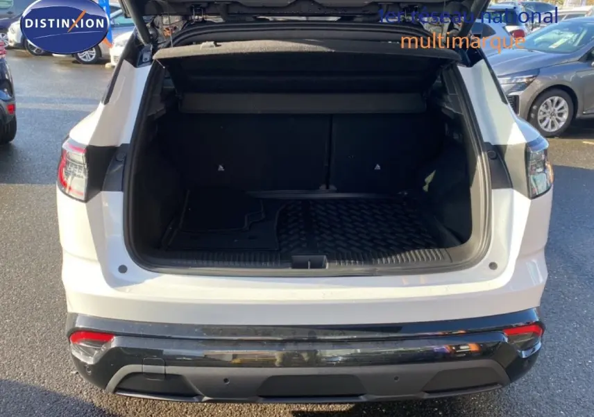 Coffre ouvert en vue arrière d’un Renault Austral blanc nacré avec toit noir, stationné en extérieur.