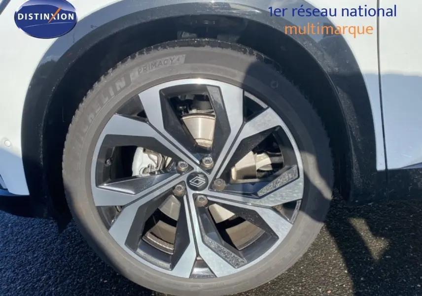 Gros plan sur la roue avant droite du Renault Austral blanc nacré avec jante alu bicolore design moderne.