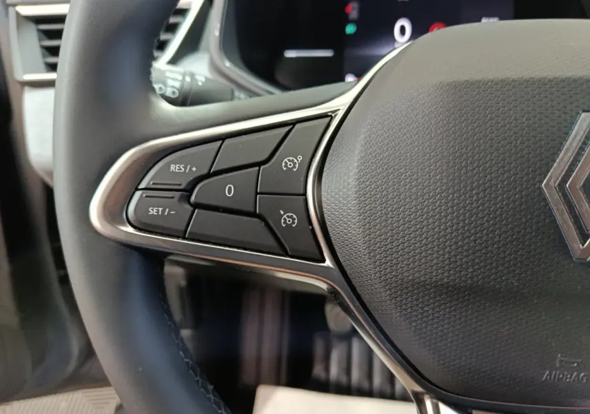 Gros plan sur le volant cuir noir de la Renault Clio 2025 avec commandes de régulateur de vitesse à gauche.