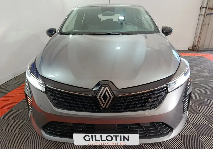 Vue avant rapprochée de la Renault Clio Evolution Blue dCi 100 gris clair avec calandre noire et feux LED allumés.