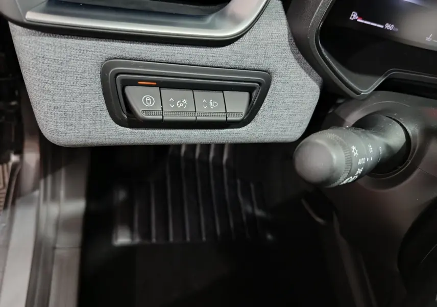 Gros plan sur les commandes sous le tableau de bord gris clair de la Renault Clio Evolution Blue dCi 100, côté gauche du conducteur.