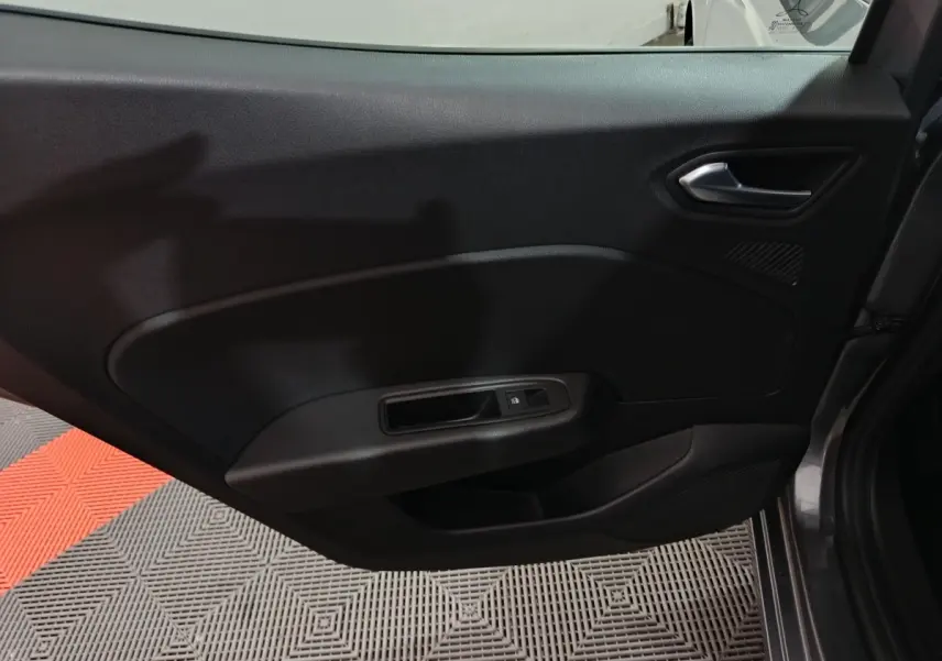 Vue intérieure côté droit de la porte avant d'une Renault Clio gris clair avec poignée et commande de vitre électrique.
