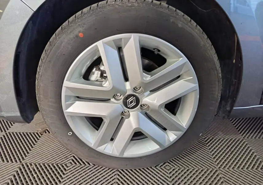 Gros plan sur la roue avant gauche grise d'une Renault Clio Evolution Blue dCi 100, jante alliage à cinq branches.