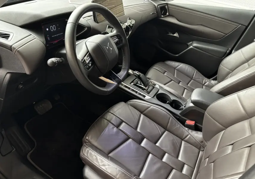 Vue intérieure côté conducteur du DS3 2024 avec sièges cuir gris foncé et tableau de bord digital moderne.