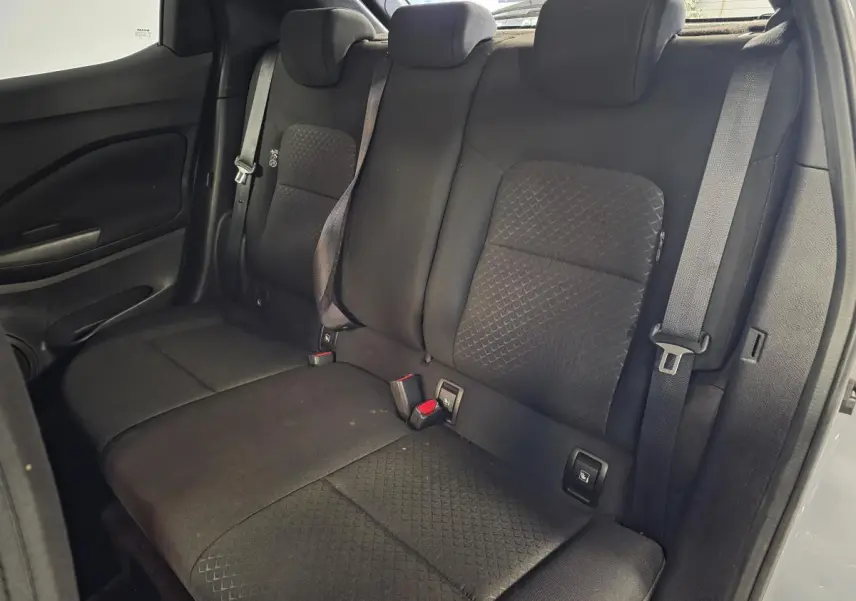 Vue intérieure de la banquette arrière noire du Nissan Juke 2023 avec trois appuis-tête réglables et ceintures de sécurité.