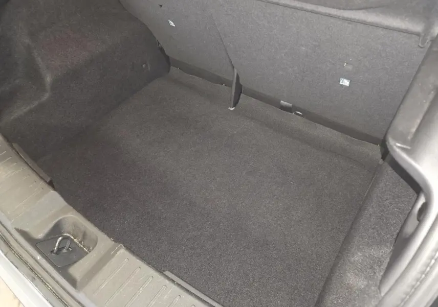 Coffre spacieux de Nissan Juke gris 2023 vu de dessus, avec revêtement intérieur noir et crochet de fixation.