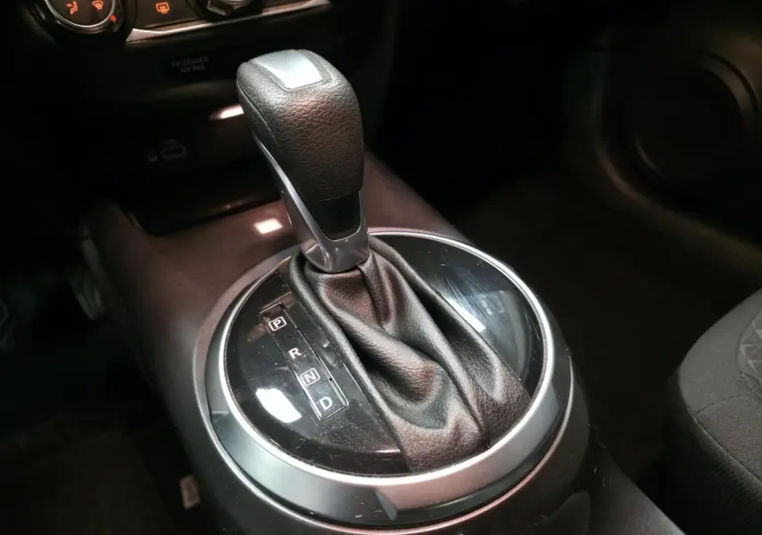 Gros plan sur le levier de vitesses automatique noir et argenté dans l’habitacle du Nissan Juke gris 2023.