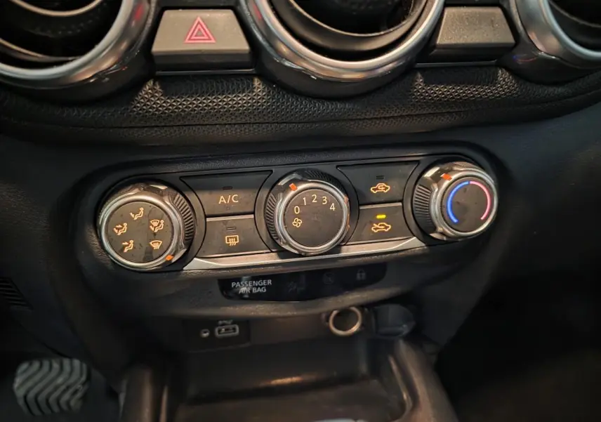 Vue rapprochée des commandes de climatisation et ventilation du tableau de bord noir du Nissan Juke 2023 gris.